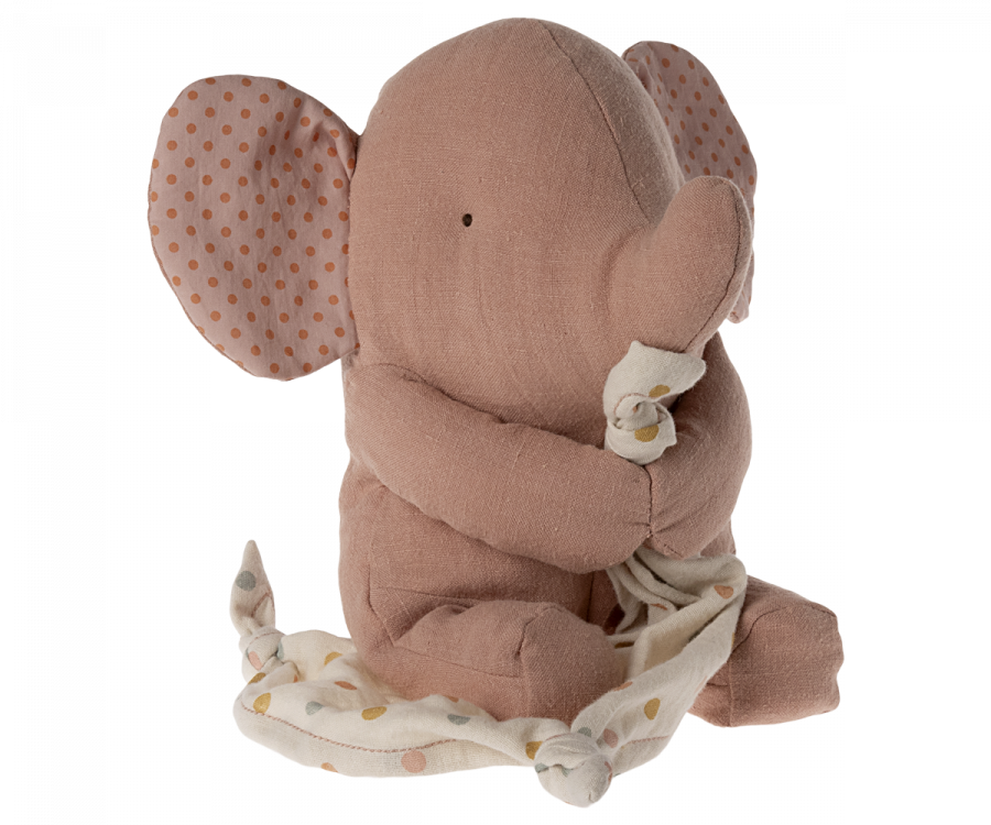 A soft, plush elephant toy with pink fabric and polka-dotted ears holds a cream-colored blanket with gold polka dots. The Maileg Lullaby Friends - Elephant - Old Rose (Plays Music) is sitting and looking to the side, giving a cuddly and endearing appearance, making it an ideal addition to any baby gift box.