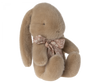 Light brown plush bunny with light pink floral bow around its neck. 