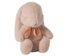 The Maileg Small Plush Bunny - Powder is a delightful toy that sits upright with its soft, light pink fur and long ears. Its cozy appearance is enriched by the plush fabric and polyester filling, while a delicate pink ribbon around its neck adds a charming touch. This bunny's fluffy charm beckons endless snuggles.