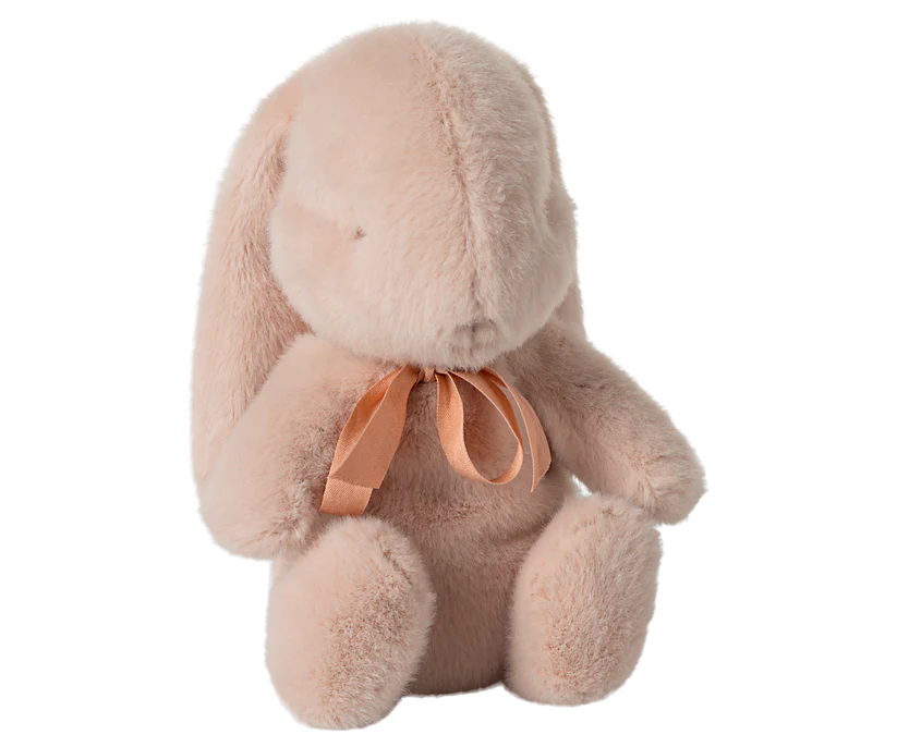 The Maileg Small Plush Bunny - Powder is a delightful toy that sits upright with its soft, light pink fur and long ears. Its cozy appearance is enriched by the plush fabric and polyester filling, while a delicate pink ribbon around its neck adds a charming touch. This bunny's fluffy charm beckons endless snuggles.