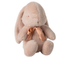 The Maileg Medium Plush Bunny - Powder is a soft, plush toy crafted from recycled polyester, featuring long ears and a pink ribbon around its neck. This light beige bunny sits upright and has an endearing design, making it perfect for cuddles.