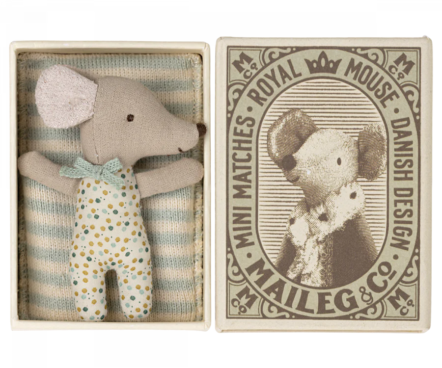 a small mouse doll inside a match box, sleeping with a blanket.