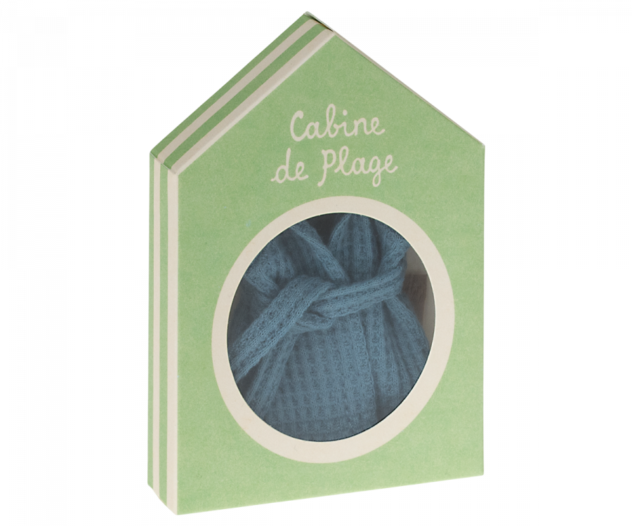 A green house-shaped gift box with a circular window displaying a folded blue Maileg Extra Clothing: Bathrobe - Dusty Blue inside. The box has white text at the top that reads "Cabine de Plage.