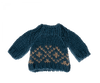 The Maileg Extra Clothing: Christmas Knitted Sweater for Dad Mouse is a small, blue knitted sweater with long sleeves and a round neck. This cozy, thick sweater features a Scandinavian pattern of beige diamond shapes near the bottom hem, making it perfect for cold weather.