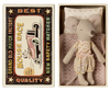 A small gray mouse toy, part of the Maileg Bathroom Starter Set, is nestled in a matchbox bed with a pink blanket and pillow, wearing a polka dot dress. The matchbox, labeled "Grand Old Match Factory" and "Mouse Race," features an illustration of a mouse driving a red car alongside the wording "Best Quality New Safety Matches.