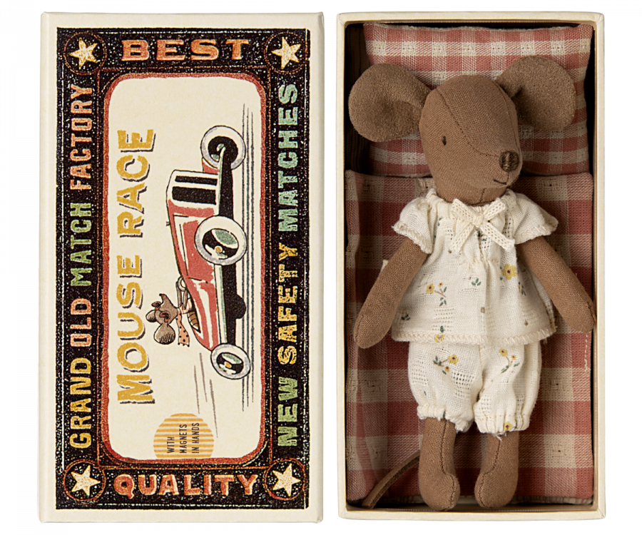 A Maileg Big Sister, Mouse In Matchbox wearing white clothes lies inside an open matchbox bed. The matchbox has a vintage design with a colorful illustration of a car and text that reads "Grand Old Match Factory," "Best Quality," "Mouse Race," and "New Safety Matches." The tiny toy is surrounded by soft fabrics.