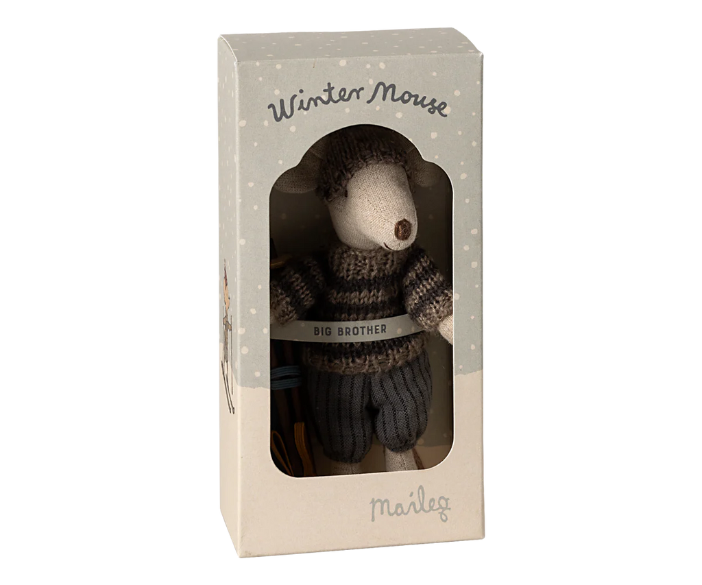 Included in the decorative box with winter-themed illustrations, you'll find the "Maileg Winter Mouse with Ski Set, Big Brother - Grey," a charming stuffed toy mouse outfitted in a knitted sweater and pants. This set even comes complete with tiny ski poles, adding an extra touch of charm and making it perfect for imaginative play during cold winter days.