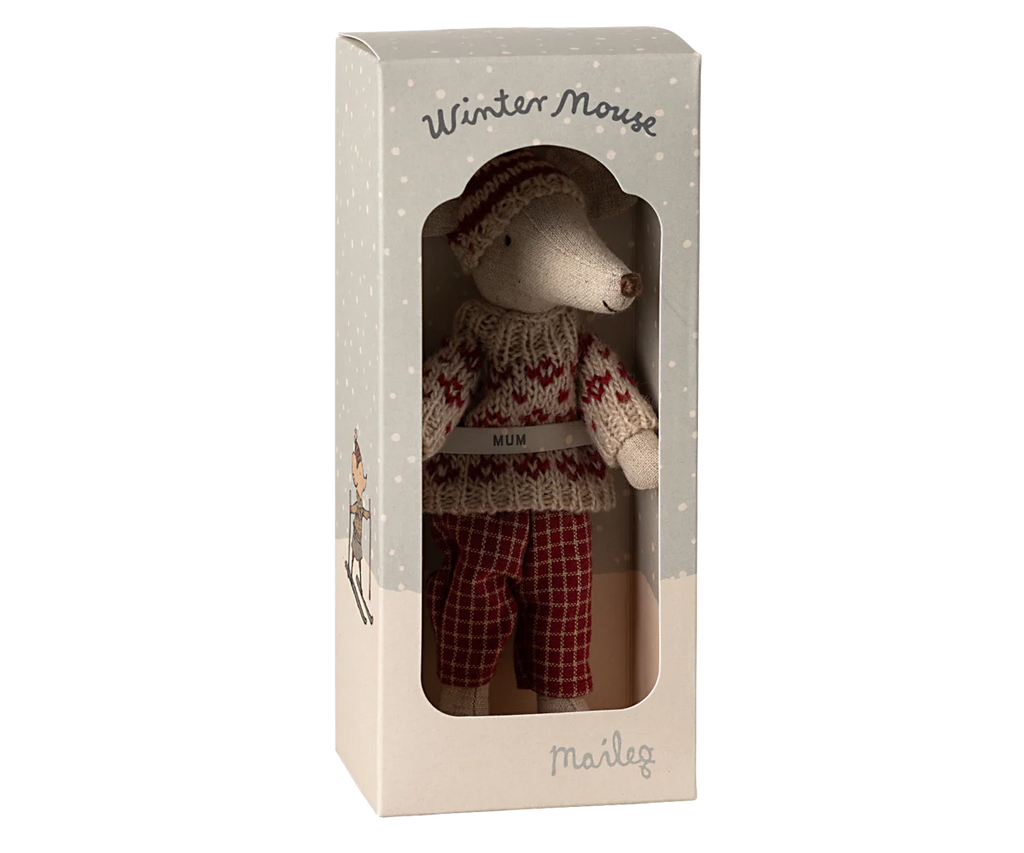 Inside a decorative box, a charming plush Maileg Winter Mouse dressed in a cozy woolen sweater and plaid pants is displayed alongside its ski set. The top of the box is labeled "Winter Mouse" while "Maileg" appears at the bottom. The window offers a glimpse into this enchanting toy, perfect for enhancing any mouse playset.