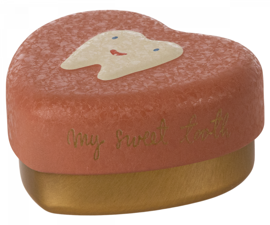 A Maileg Tooth Box with a textured surface. The lid is a light coral color and features a cute tooth illustration with a smiling face. The words "My sweet tooth" are printed in gold script on the side, perfect for holding small baby teeth and cherished childhood memories.