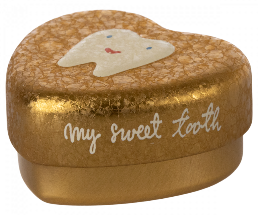 A small, heart-shaped golden box with a slightly cracked texture. The box, a perfect Maileg Tooth Box, has an illustration of a smiling tooth on the lid. The text "my sweet tooth" is written in white cursive on the side, evoking cherished childhood memories.