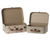 Two small, open suitcases with whimsical designs are part of the Maileg 2 Piece Suitcase Set. The larger suitcase on the left showcases delightful drawings of animals, trees, and rainbows against a light beige background. Meanwhile, the smaller suitcase on the right boasts a lush green leaf pattern set on a pink background. Both suitcases have brown handles and are perfect for adding charm to your storage solutions.