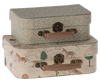 Two decorative suitcases from the Maileg 2 Piece Suitcase Set are stacked. The top suitcase, crafted from Maileg fabrics, features a floral pattern with green leaves and red dots, while the bottom one displays a whimsical design with horses, trees, and rainbows. Both suitcases have beige handles and antique-style metal clasps—perfect for stylish storage.