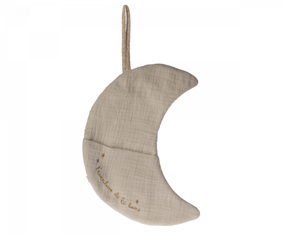 A soft, light beige crescent moon-shaped pillow with a small hanging loop at the top, perfect for children's room decor. The pillow has the text "Ici c'est la lune" embroidered on it with three small stars around the text. The texture appears gently crumpled, giving this Maileg Moon Decoration, L'aventure De La Lune a cozy look.