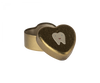 A small, heart-shaped Maileg Tooth Box with a gold exterior. The lid is slightly open, revealing the inside. The lid is decorated with an illustration of a smiling tooth, evoking childhood memories of keeping small baby teeth safe within this metal heart.