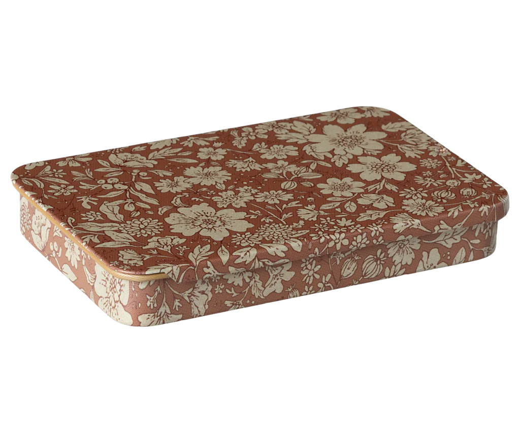 The Maileg Metal Box with Sliding Lid features a rectangular shape and is covered in floral-patterned fabric. Its red-brown color, adorned with cream-colored flowers and leaves, gives it a vintage charm—perfect as a stylish storage solution or gift card box.