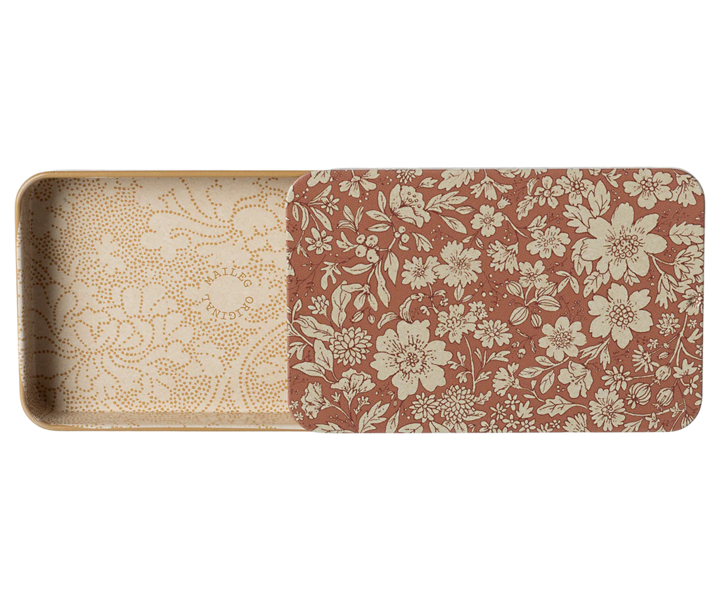 The Maileg Metal Box with Sliding Lid is a rectangular metal container featuring a partially open lid. The lid boasts a brown background with an intricate white floral pattern, while the inside of the storage box is decorated with a delicate, patterned design in white.