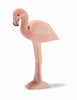 The Ostheimer Flamingo, a wooden figurine painted in light pink and standing on one leg, features a curved black beak and simple carved details representing its wings and body. This handcrafted toy, reminiscent of Ostheimer's signature style, is set against a plain white background, inviting imaginative play.