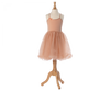 A Maileg Princess Tulle Dress - Melon displayed on a wooden mannequin stand. The sleeveless dress features a soft bodice with a small flower detail on the left strap and a fluffy, tutu-style tulle skirt, fitting perfectly into any magical wardrobe, evoking fairytale dreams.