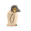 The Ostheimer Penguin, Small is a handcrafted wooden toy featuring a light beige body, gray-black head, and a yellow eye patch. This simple and stylized figure stands upright, facing slightly to the right, and is made with minimal details from sustainably sourced materials.