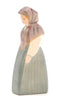 The Ostheimer Market Woman is a wooden figurine featuring a person dressed in a hooded shawl and a long dress. Painted in pastel shades of blue and beige, this upright figure showcases simple, handcrafted details that are characteristic of Ostheimer toys, designed to inspire imaginative play.