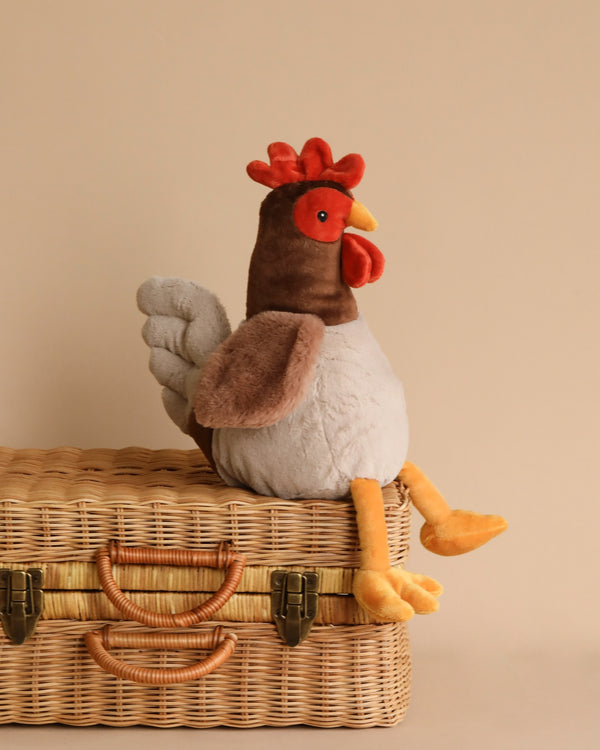 Randy the Rooster, a soft and snuggly stuffed chicken, perched on a wicker suitcase.