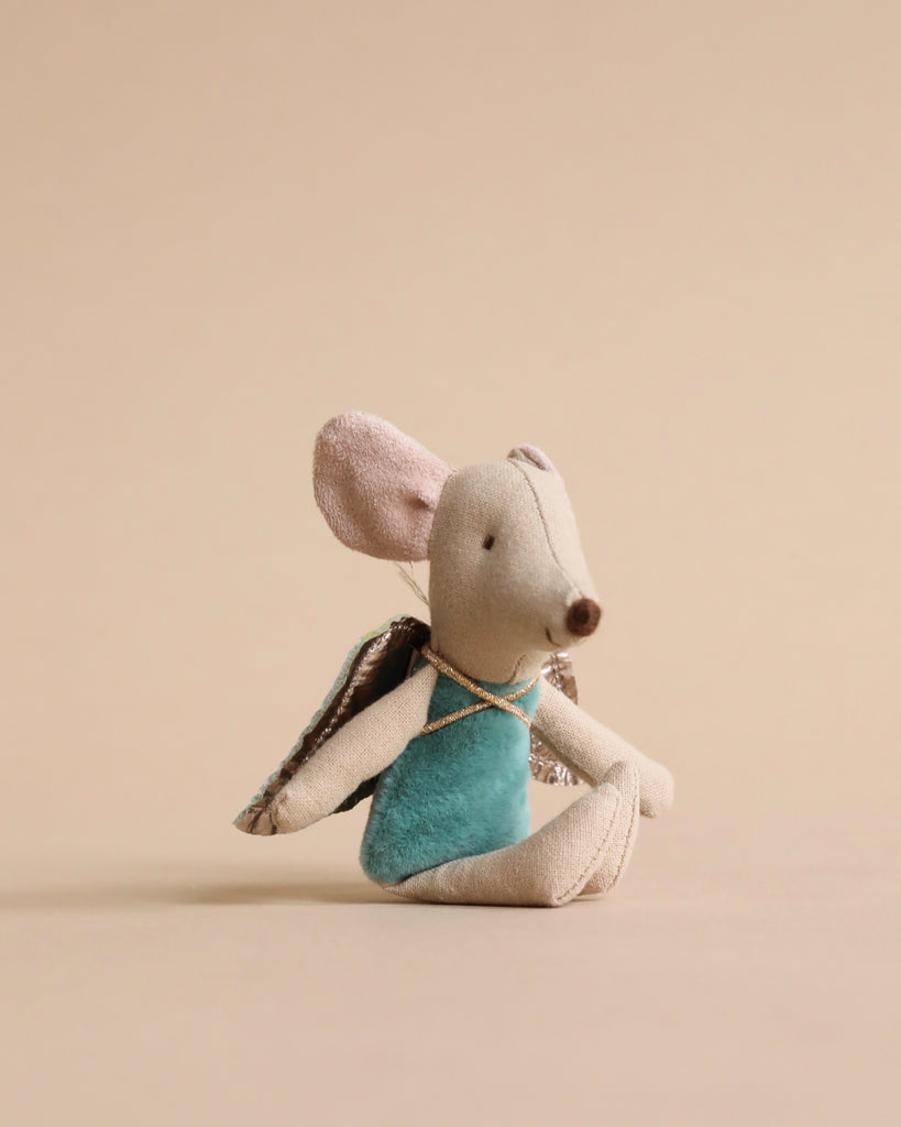 A Maileg Fairy Angel Mouse - Mint with a soft brown body, large ears, and a teal blue outfit sits against a plain beige background. The fairy mouse also has tiny, delicate wings attached to its back, ready to create magical moments and inspire wonderous stories.