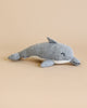 The Knit Alpaca Dolphin, a small and handcrafted plush toy with a light gray top and white underside, rests on a beige background. Hailing from Peru, this dolphin displays a closed-mouth smile and small, sewn eyes, embodying the charm of a cute and cozy stuffed animal.