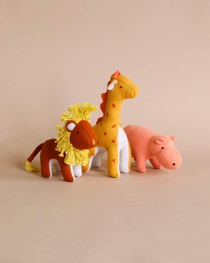 Three Olli Ella Holdie Folk Felt Savannah Animals, a lion, giraffe, and hippopotamus, made of felt and displayed against a light beige background.