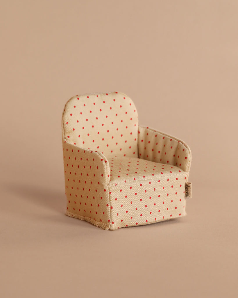 A Maileg Chair, Mouse - Dot, with red polka dots and a beige hue sits charmingly against a neutral background, perfect for accommodating small Maileg friends in their enchanting Gingerbread House.