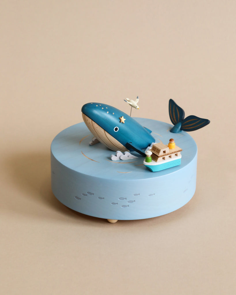 Wooden ocean themed music box with a blue whale in the center and a boat going around it. 