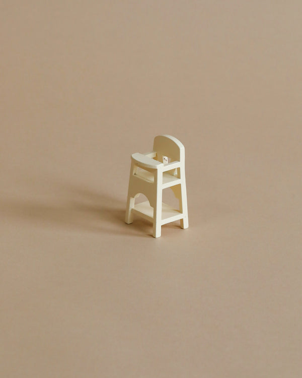 A small, white Maileg Mouse Size High Chair on a plain beige background, showcasing a minimalist design and simple construction.