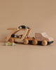 The Konges Sløjd - Wooden Car Transporter is a delightful set featuring a wooden truck and car carrier, complete with small race cars, all made from FSC-certified beech wood. The minimalist designs in natural wood tones contrast beautifully against a neutral beige backdrop, providing timeless playtime enjoyment.