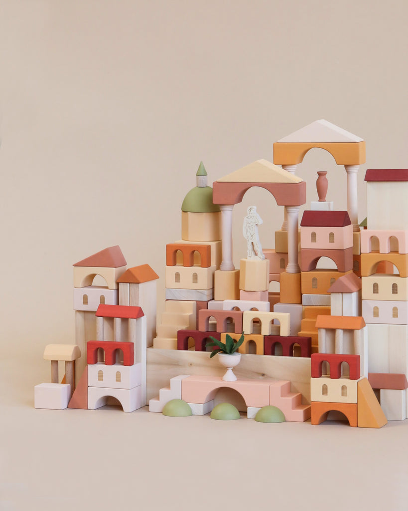 A toy wooden castle built with Sabo Concept Italian Ancient City Blocks featuring archways, towers, and a few green spherical elements, assembled on a light beige background.