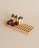 A Crayon Tray For Stockmar -24 x 24 Slots, crafted from Linden wood, holds a variety of colorful Stockmar sticks and blocks, organized neatly against a plain beige background.