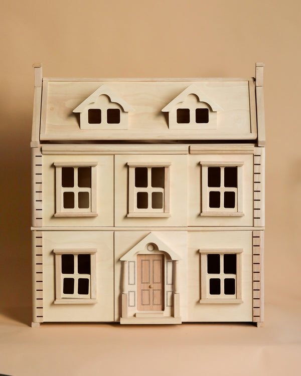 The PlanToys Victorian Dollhouse is a sustainably crafted wooden dollhouse with a natural finish, featuring a symmetrical facade and a triangular roof. It includes six framed windows and a centered door, all set against a plain beige background.