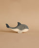 An Ostheimer Whale is placed against a beige background. The whale, with blue-grey and white coloring, has a simple, smooth design featuring a prominent dorsal fin, a curved tail fin, and a small eye—perfect for imaginative play.