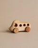 A Handmade Wooden Bus with a smooth finish and rounded edges, featuring visible wood grain, two large wooden wheels, and five circular windows, on a plain beige background.