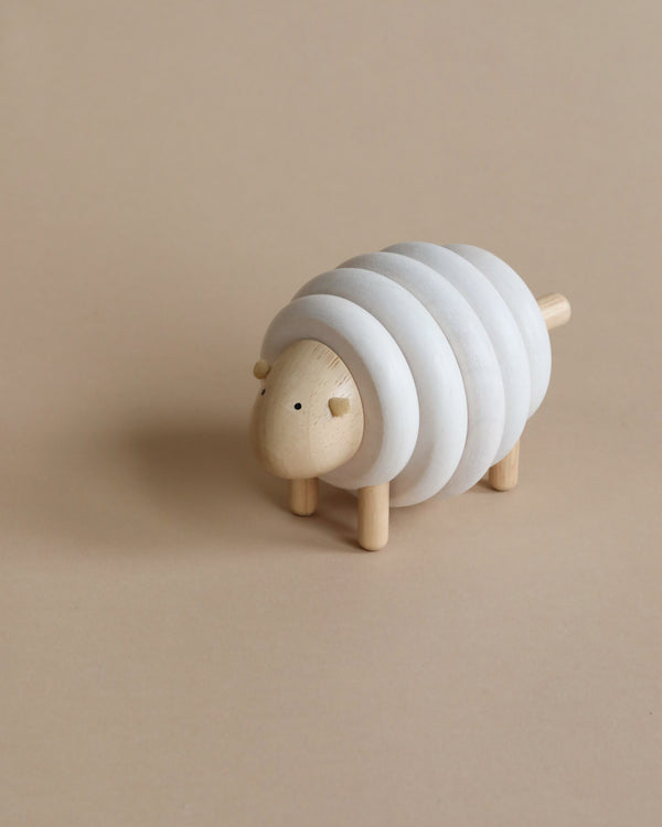 A Lacing Wooden Sheep shaped like a sheep with layered rings forming its body, standing on a beige background.