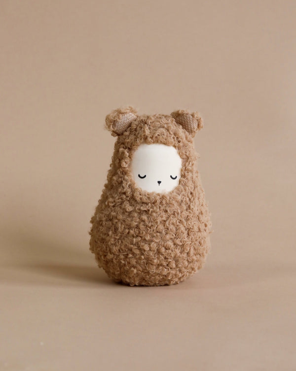 A cute, Handmade Musical Roly Poly - Bear toy resembling a fluffy sheep with a serene face and tiny ears, set against a soft neutral background.