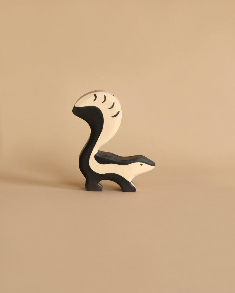 A minimalist Holztiger Skunk, reminiscent of HOLZTIGER figures, stands on a plain beige background with a black and white color palette. Its tail is prominently arched over its back, showcasing the simple yet abstract design. Made in Europe from handcrafted wood.