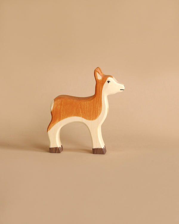 A minimalist wooden figurine of a deer, handcrafted in Europe by Holztiger Deer, is set against a simple beige background. The figurine is painted with a brown and white color scheme, capturing a graceful yet simplistic design.