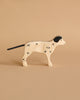 A Holztiger Dalmatian Dog with Dalmatian-like black spots and a black ear, made from high-quality maple and beech wood. Standing against a plain beige background, the dog has a black tail and is depicted in a side profile view.