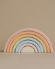 A Handmade Rainbow Stacker - Pastel with soft pastel shades of pink, peach, blue, and cream arranged in ascending arches against a plain beige background.