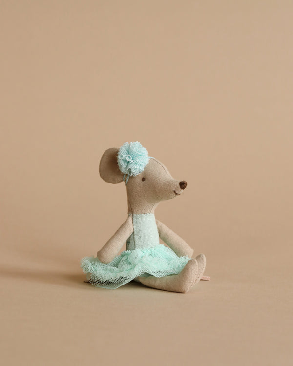 A handmade plush Maileg Ballerina Mouse - Little sister (Light Mint) in a sitting position, wearing a teal tutu and a matching flower on its ear, against a soft beige background.