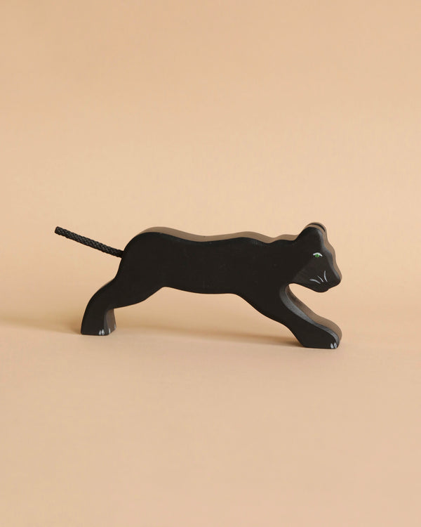 A small, sleek black Holztiger Panther with a minimalist design is shown in a side view, appearing to be in a poised, walking stance. Handcrafted from wood and part of the renowned HOLZTIGER figures, it exudes simple elegance against the plain light beige background. Made in Europe.