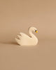 A minimalist Holztiger Swan, Swimming with a simplistic design featuring a white body, a yellow beak, and black eyes. This handcrafted wood toy is made in Europe and displayed on a beige background.