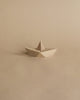 Sentence with Product Name: A Boyhood Admiral, Small Oak origami-style boat on a plain beige background, featuring a neatly folded design with geometric symmetry and visible wood grain.