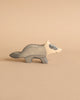 A small, handcrafted wooden figurine of a badger with a minimalist design. Made from maple and beech wood, the badger stands on all fours and is painted in shades of grey and white against a beige background. The carving style is smooth, similar to HOLZTIGER figures, giving it a simple and charming appearance.