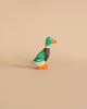 A Holztiger Mallard featuring a green head, brown neck, and orange beak stands on a plain beige background. The handcrafted wood duck has vibrant colors and is crafted in a simple, minimalist style, reminiscent of HOLZTIGER figures made in Europe.