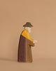 This Ostheimer Nativity Scene figurine showcases an elderly person in a long robe and hat, holding an item against a light brown backdrop. Expertly handcrafted in shades of brown, yellow, and gray, it beautifully inspires imaginative play.